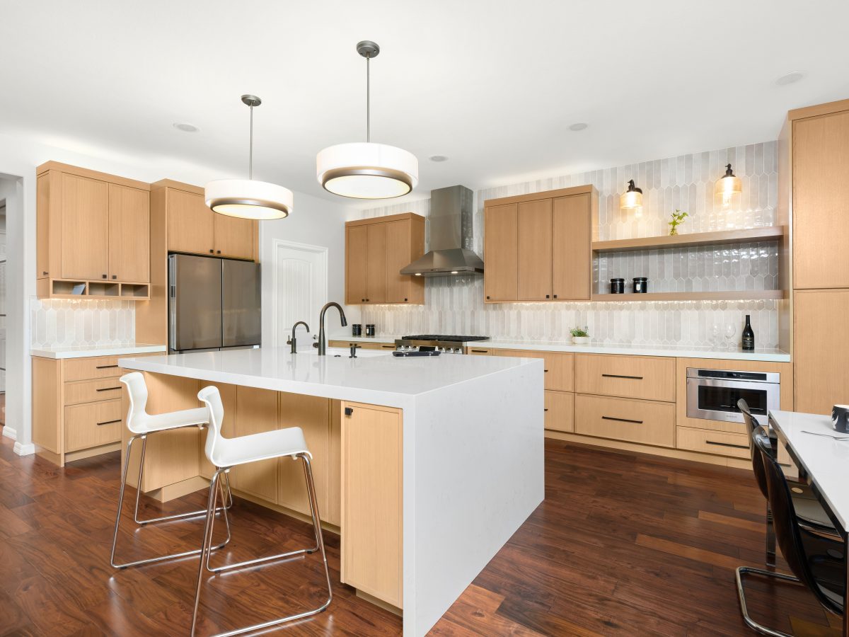 Warm oak shaker kitchen with quartz island, picket tile backsplash, and dark bronze fixtures — Reveal Interior Design Las Vegas
