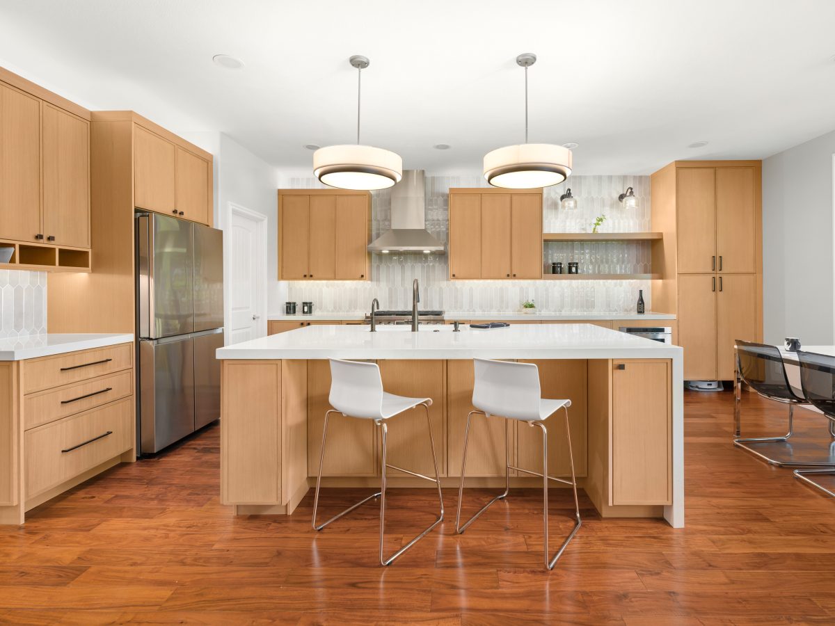 Warm oak slim shaker kitchen with quartz island, handmade-style picket backsplash tile, and dark bronze fixtures — Reveal Interior Design Las Vegas