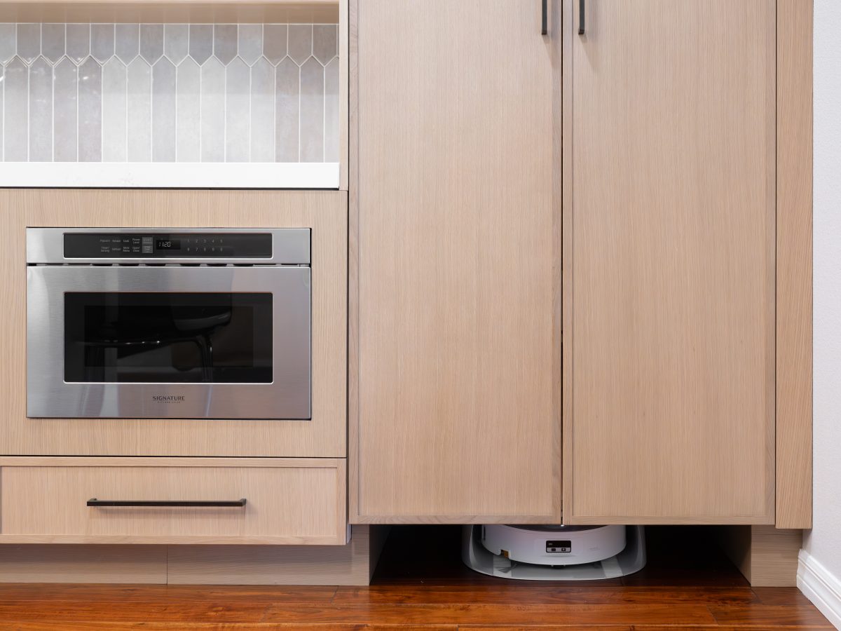 Kitchen with warm stained oak slim shaker cabinetry and dark bronze hardware featuring custom appliance tower — Reveal Interior Design Las Vegas