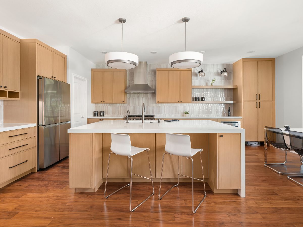Warm oak slim shaker kitchen with quartz island, handmade-style picket backsplash tile — Reveal Interior Design Las Vegas