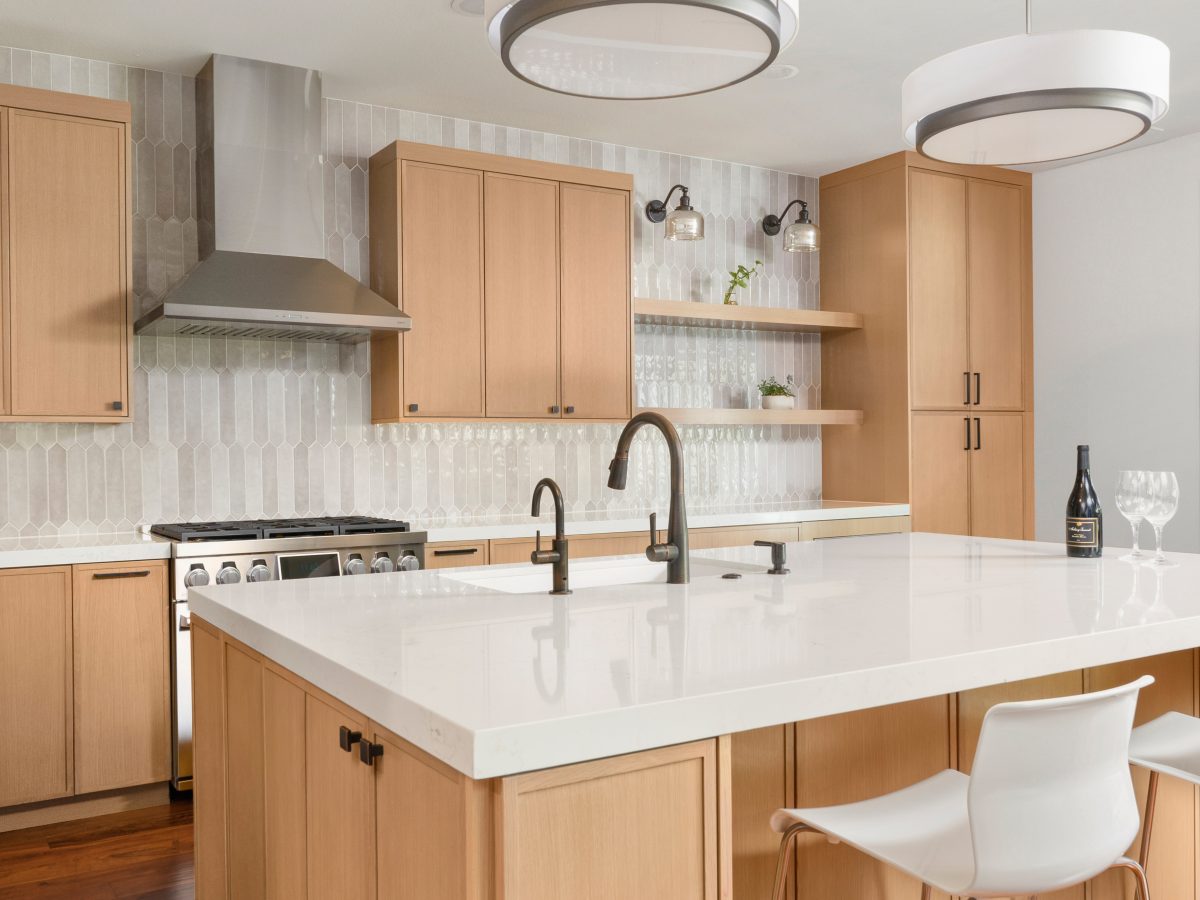 Warm oak kitchen with quartz island, handmade-style picket tile backsplash, and dark bronze fixtures — Reveal Interior Design Las Vegas