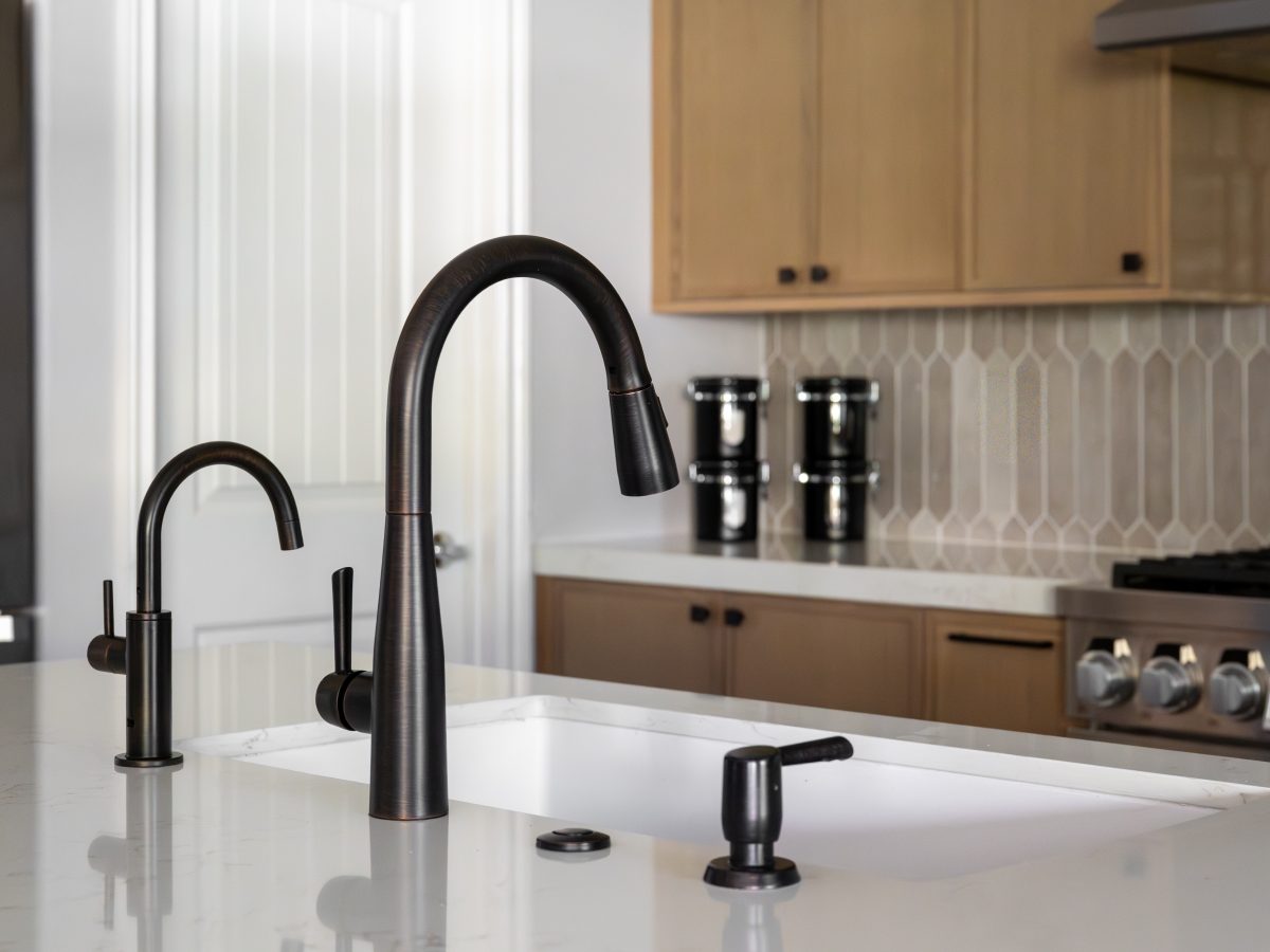 Kitchen island sink with dark bronze faucet fixtures and warm off-white quartz countertops — Reveal Interior Design Las Vegas