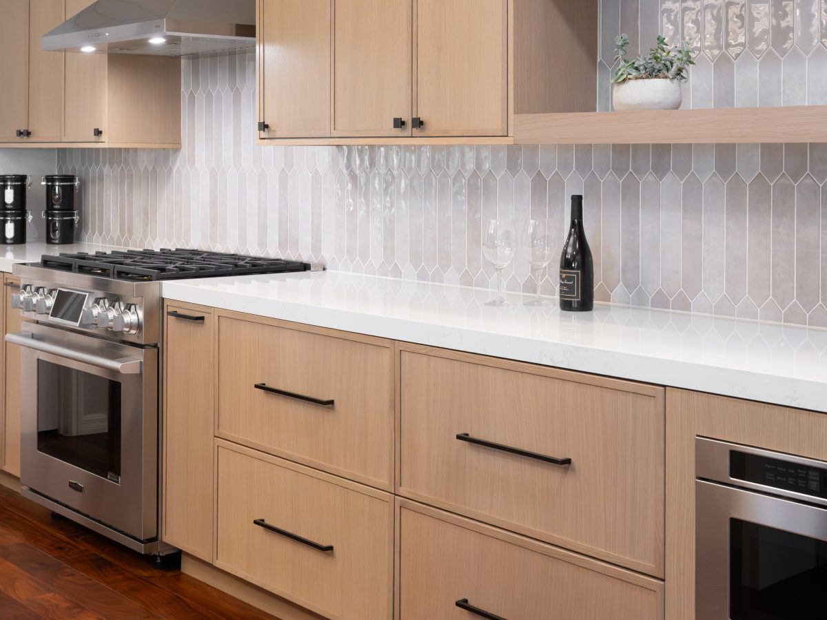 Warm oak shaker kitchen with handmade-look picket backsplash tile and quartz countertops — Reveal Interior Design Las Vegas