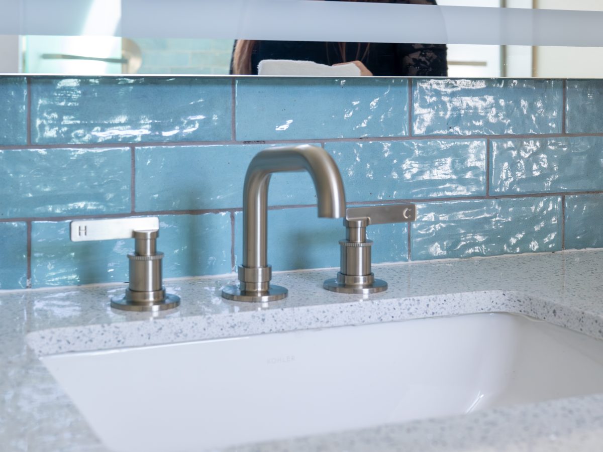 Primary bathroom vanity with white quartz countertop, brushed nickel fixtures, and handmade teal subway tile — Reveal Interior Design Las Vegas