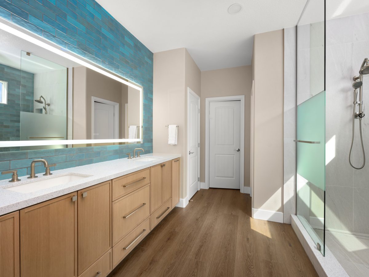 Spa primary bathroom with handmade teal subway tile, warm oak vanity, and walk-in shower — Reveal Interior Design Las Vegas