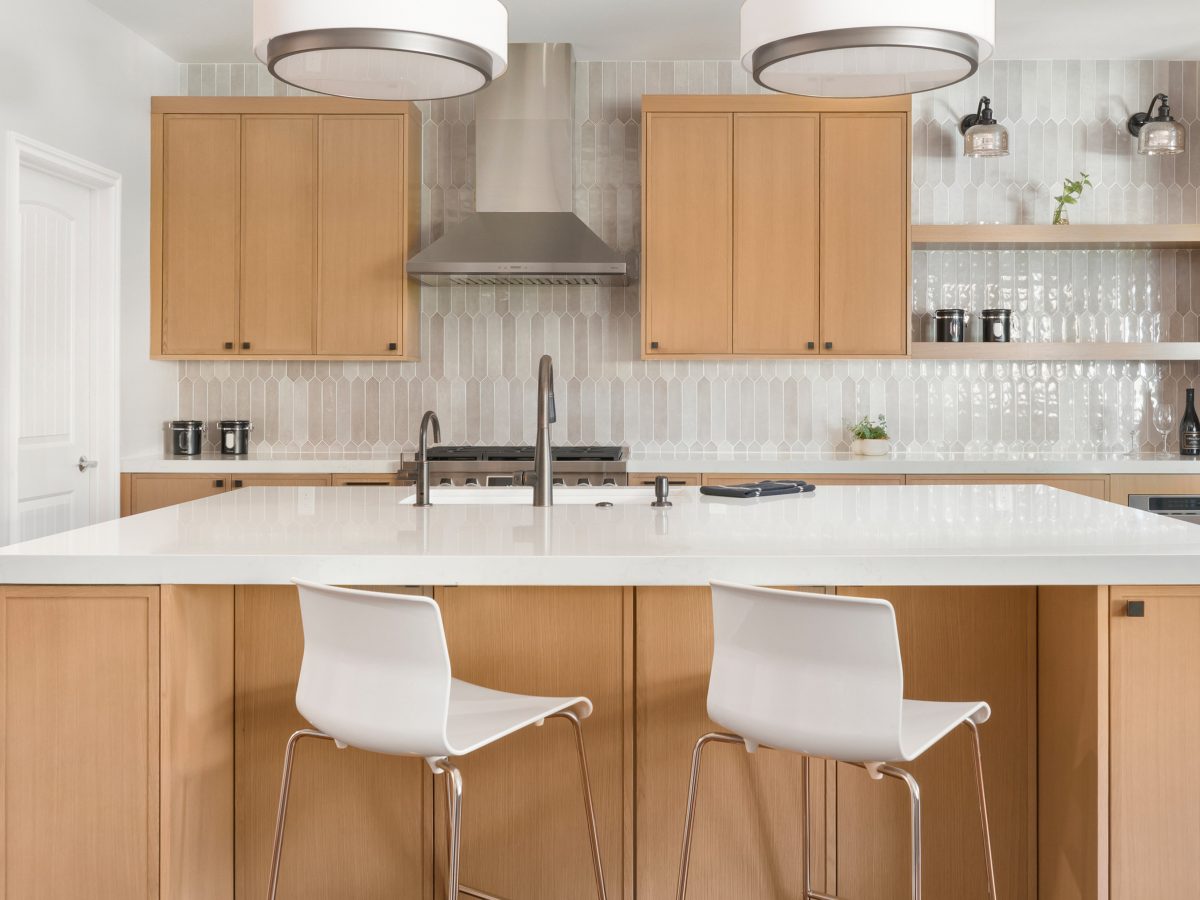 Contemporary kitchen with warm oak cabinetry and quartz island — Reveal Interior Design Las Vegas