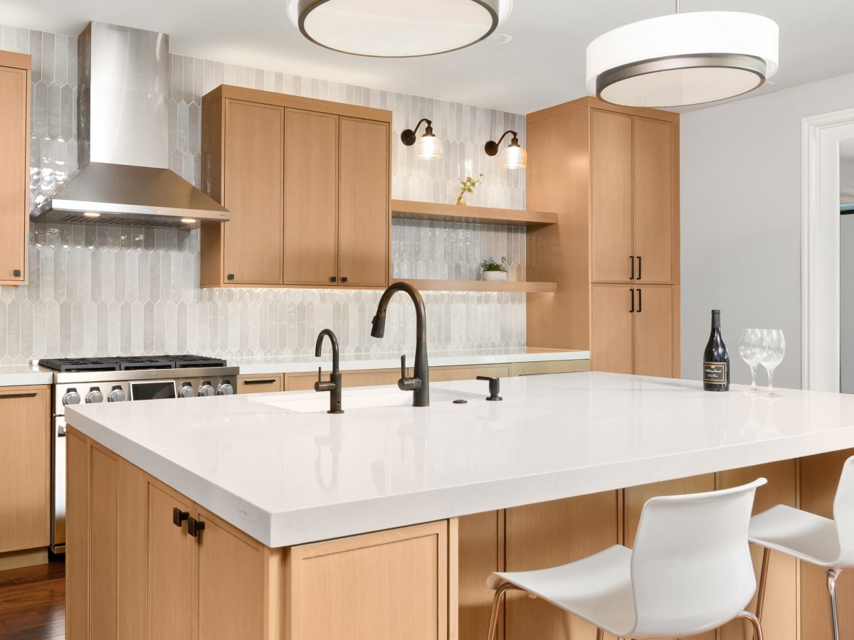 Warm oak slim shaker kitchen with quartz island, dark bronze fixtures, and handmade-look picket backsplash tile — Reveal Interior Design Las Vegas