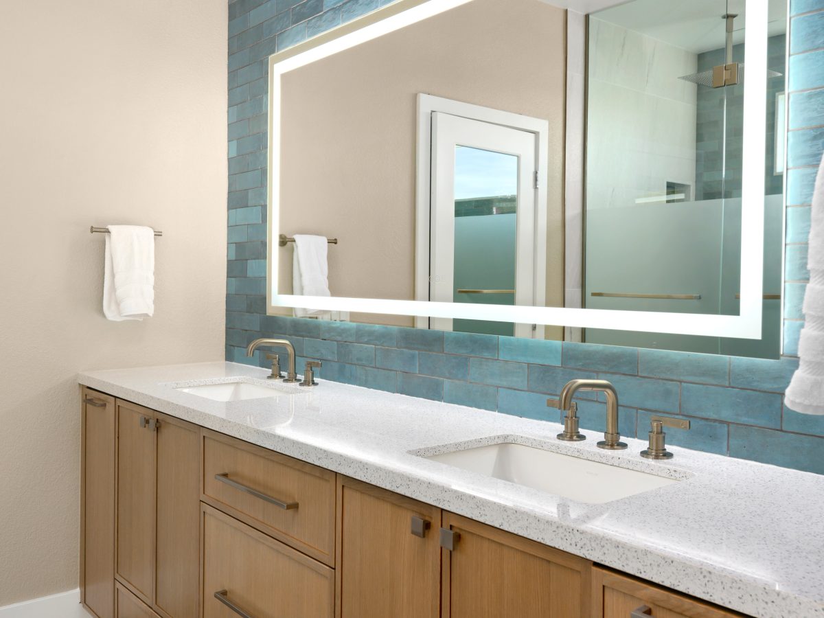 Primary bathroom double vanity with white quartz countertops and handmade teal subway tile backsplash — Reveal Interior Design Las Vegas