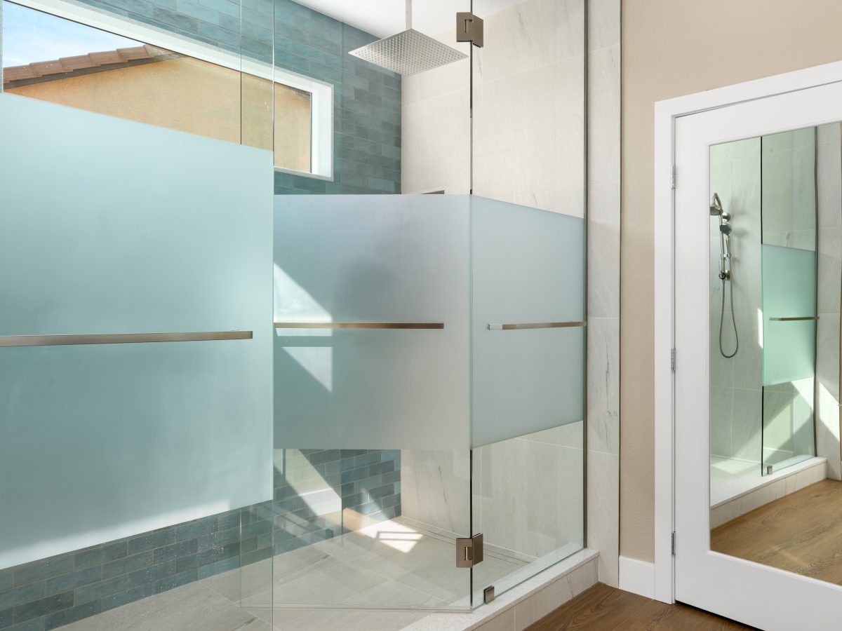 Primary bathroom walk-in shower with custom privacy glass and handmade teal subway tile — Reveal Interior Design Las Vegas