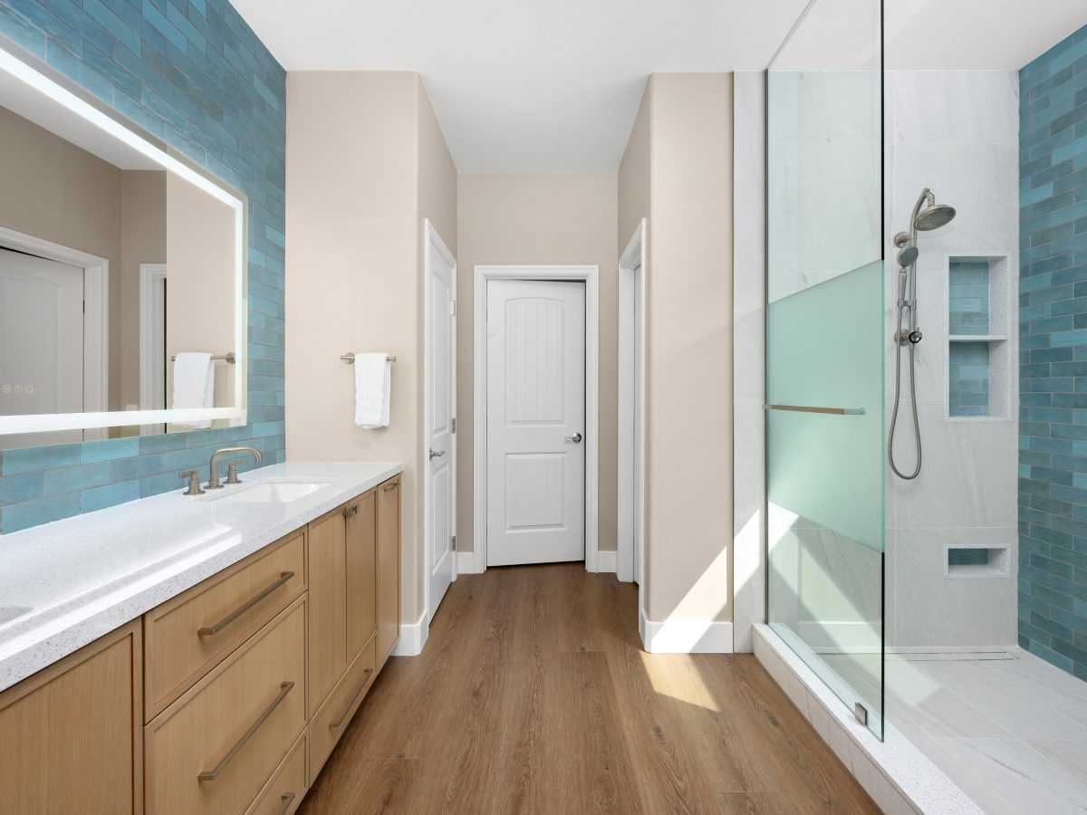Spa primary bathroom with handmade teal subway tile, two-person walk-in shower, and warm oak vanity — Reveal Interior Design Las Vegas