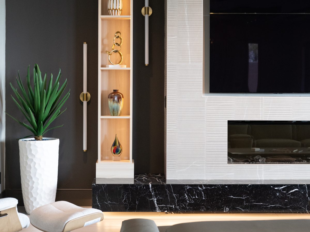 Living room with custom light wood bookcase niche, floating black marble hearth, and large linear fireplace — Reveal Interior Design Las Vegas