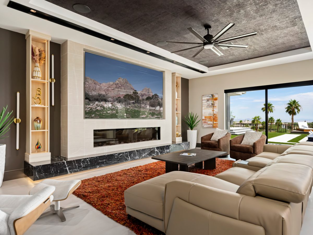 Living room with four-panel TV niche, custom light wood cabinetry, and floating black marble hearth — Reveal Interior Design Las Vegas