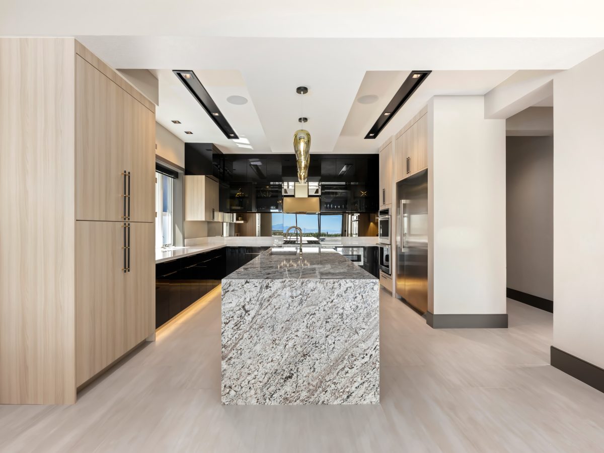 Luxury kitchen with granite waterfall island, dark charcoal and white oak cabinetry — Reveal Interior Design Las Vegas