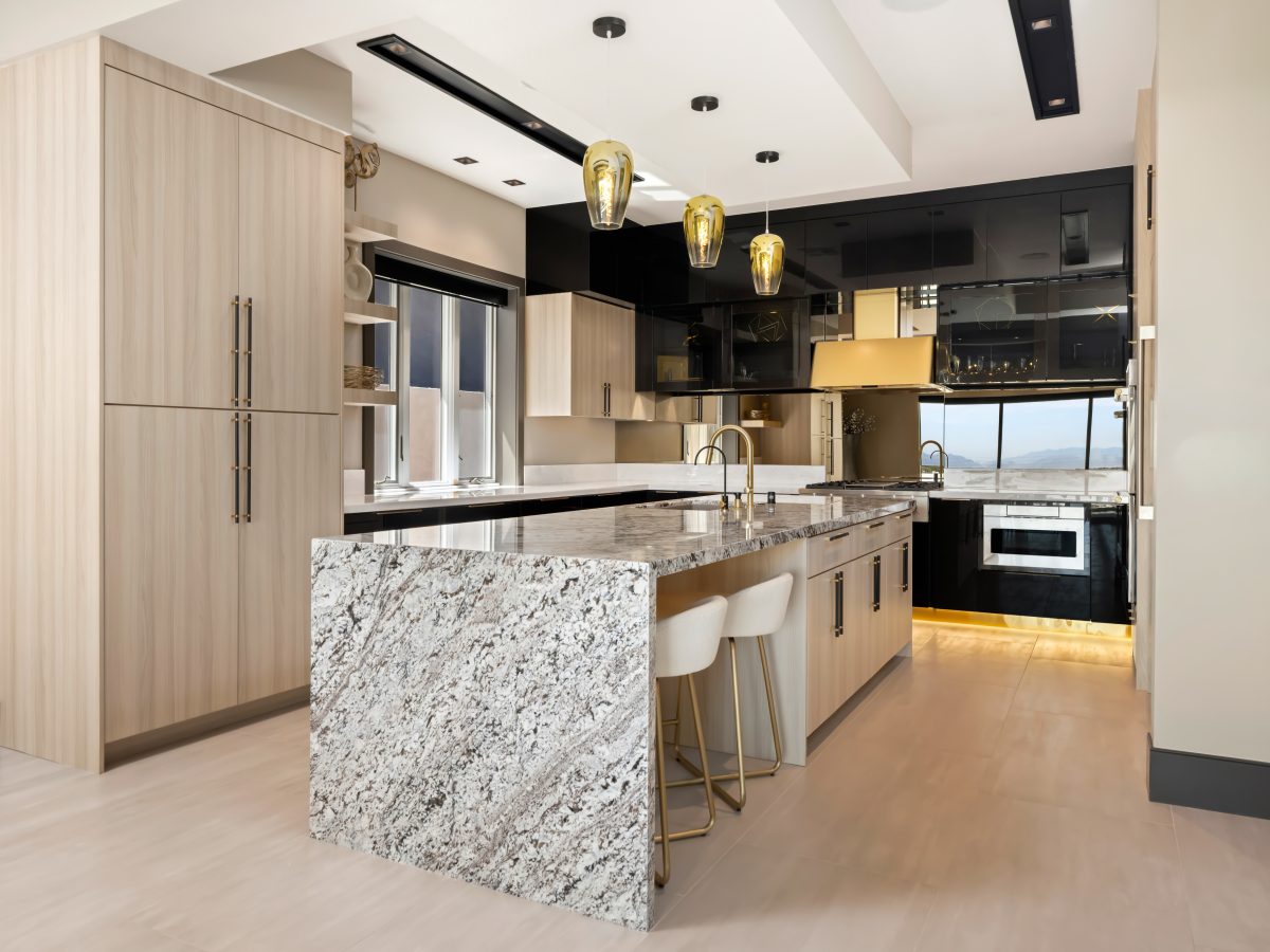 Luxury kitchen with granite waterfall island, white oak cabinetry, and mirrored backsplash — Reveal Interior Design Las Vegas