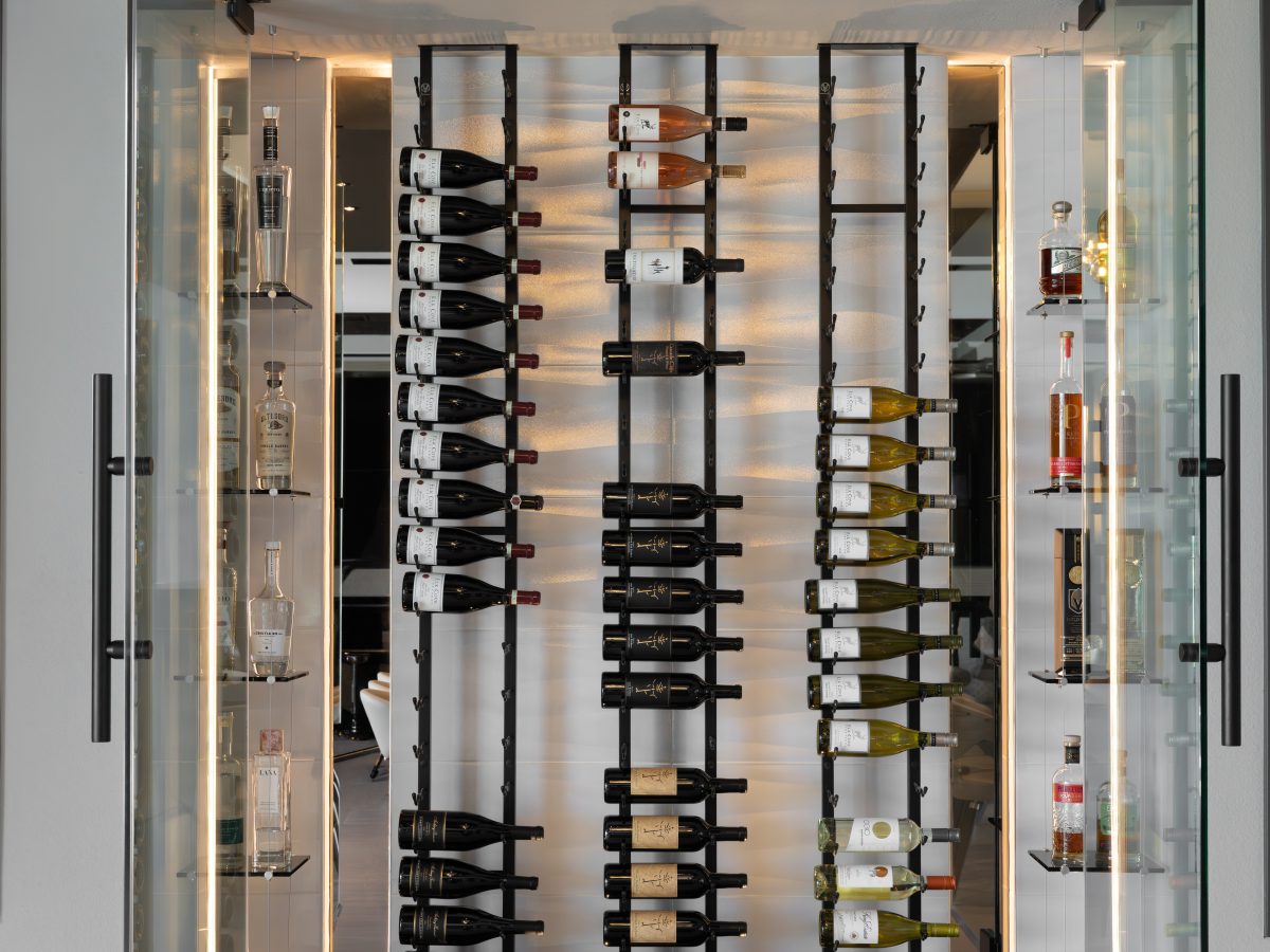 Custom wine niche with modern metal shelving, mirrored panels, and hidden LED lighting — Reveal Interior Design Las Vegas