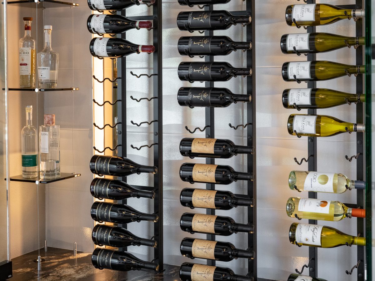 Custom wine niche with modern metal shelving, mirrored panels, and hidden LED lighting — Reveal Interior Design Las Vegas