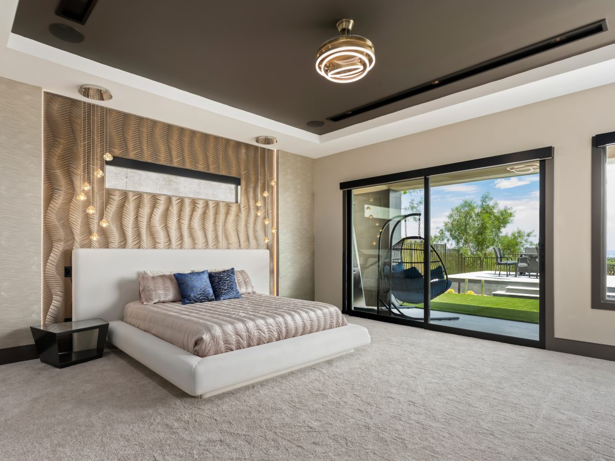 Primary bedroom with Urbane Bronze tray ceiling, gold textured wall panels, and platform bed — Reveal Interior Design Las Vegas