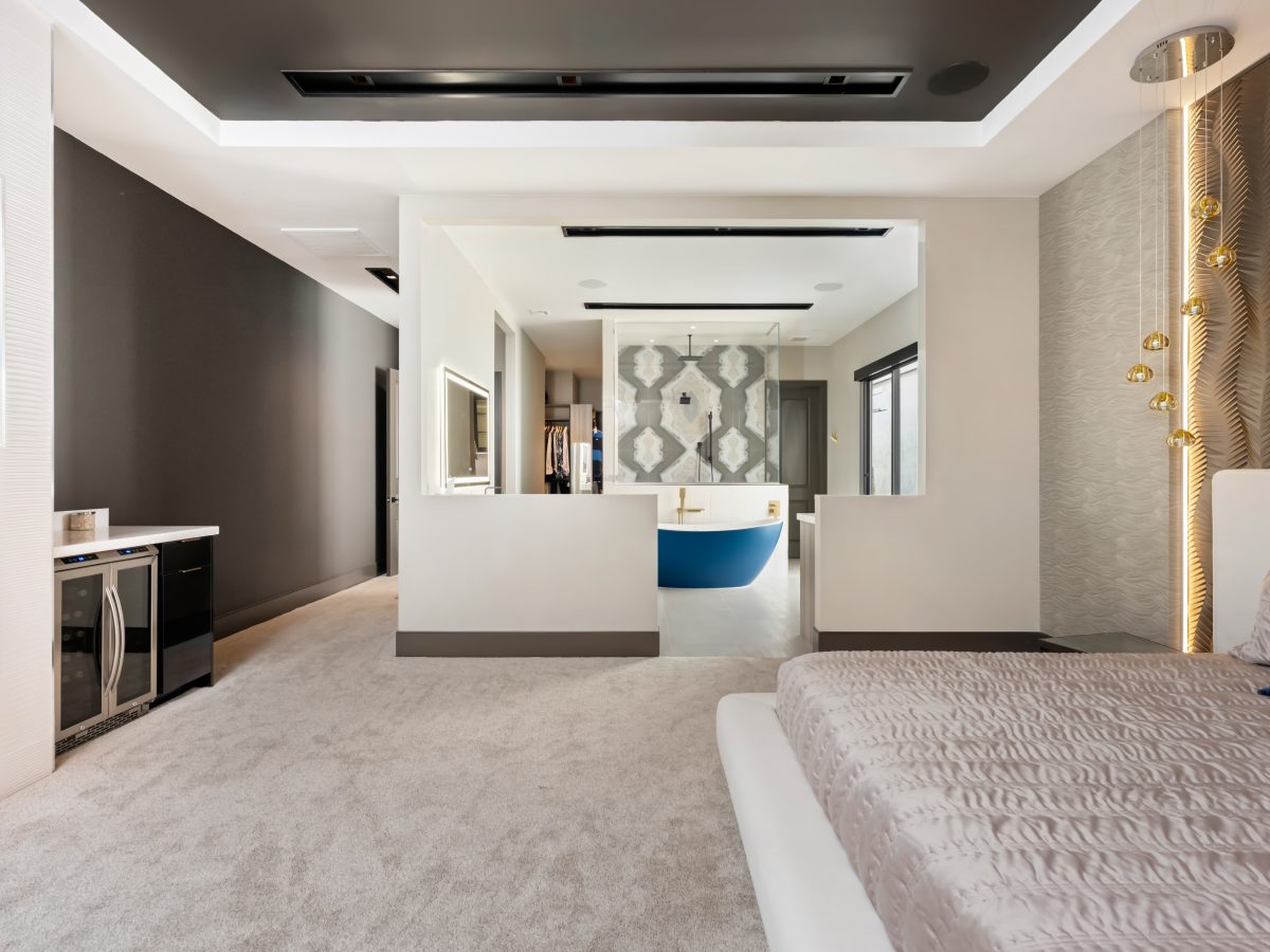 Primary bedroom with Urbane Bronze ceiling, open-plan bathroom, and gold textured wall panels — Reveal Interior Design Las Vegas