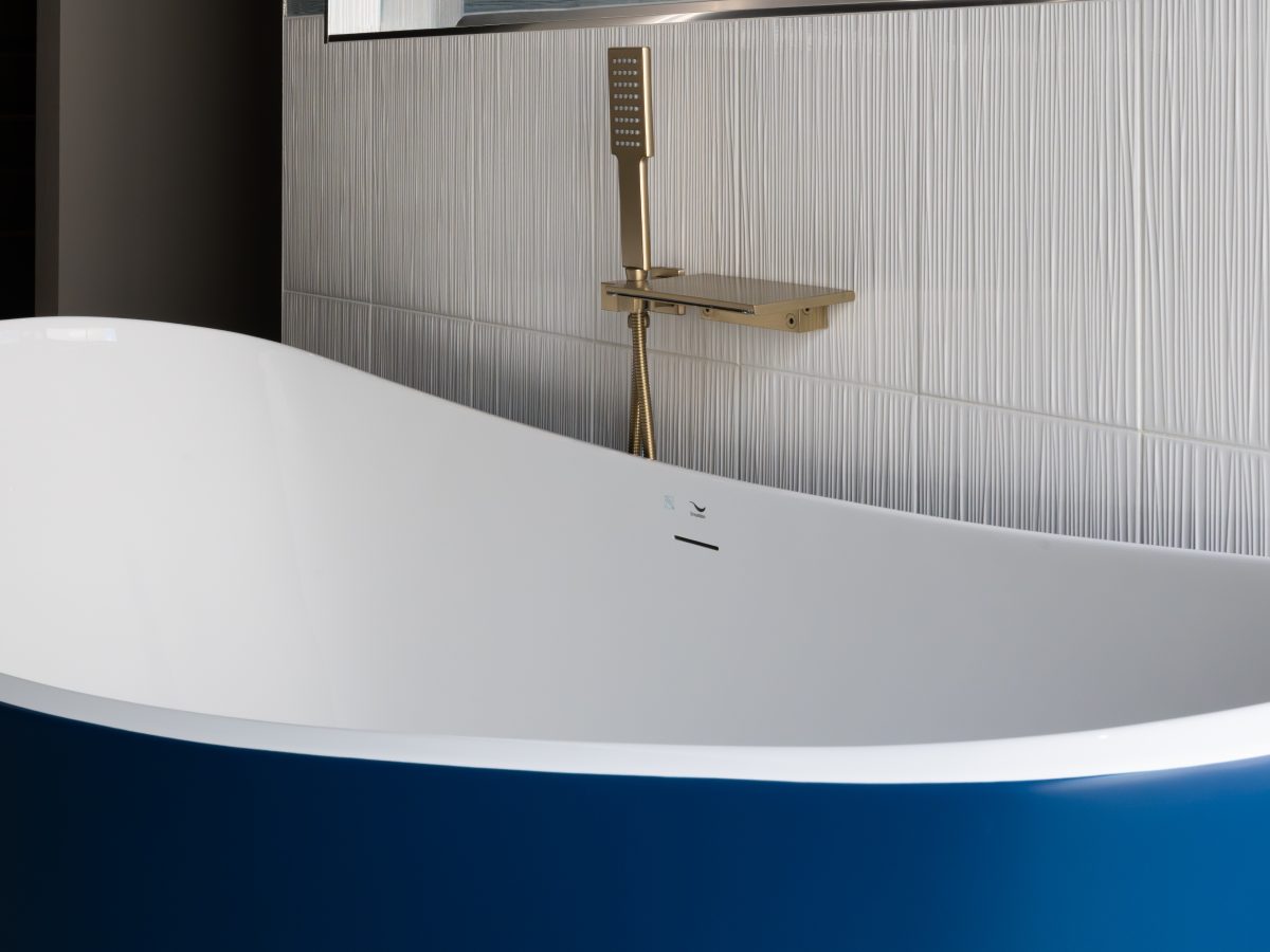 Primary bathroom with cobalt blue freestanding tub, gold fixtures, and white textured porcelain tile — Reveal Interior Design Las Vegas
