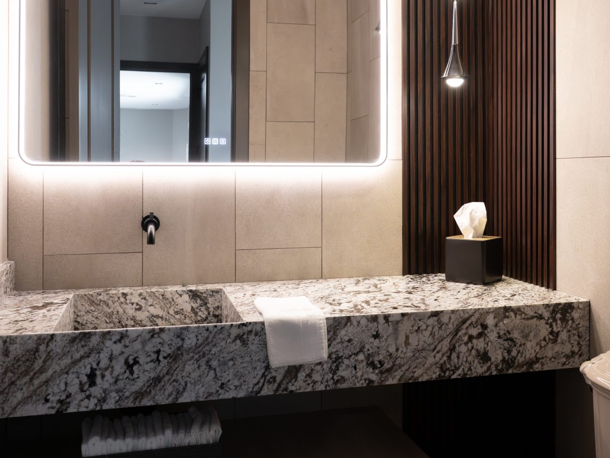 Powder bath with granite floating vanity, integrated sink, LED mirror, and multi-drop pendants — Reveal Interior Design Las Vegas
