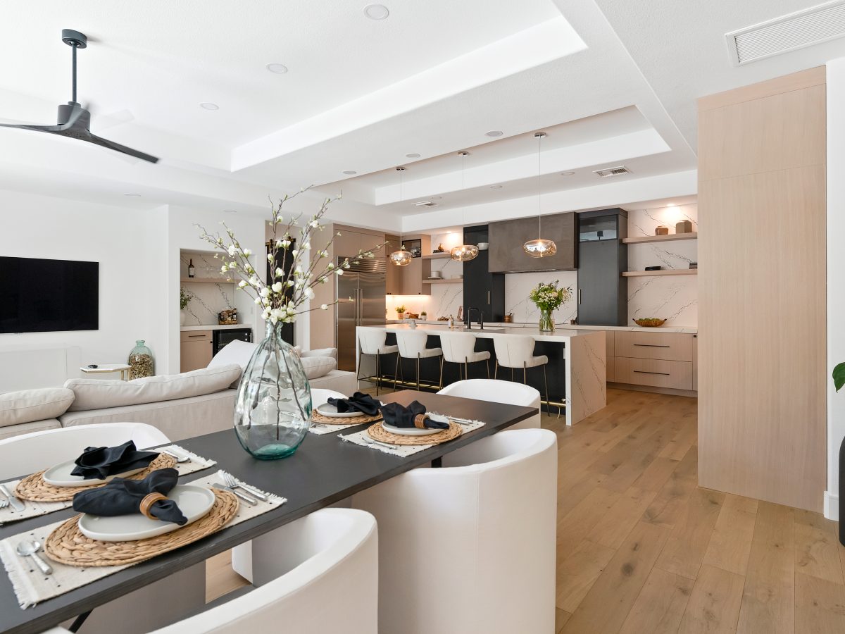 Open-concept kitchen with white-washed oak cabinetry, black quartz countertops, and matte black range hood — Reveal Interior Design Las Vegas
