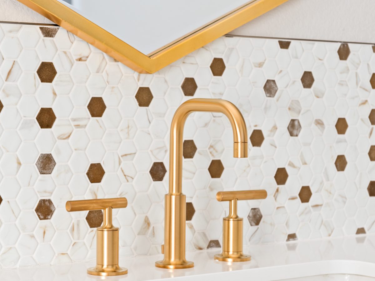 Primary bathroom vanity with gold widespread faucet and calacatta-look glass mosaic tile backsplash — Reveal Interior Design Las Vegas