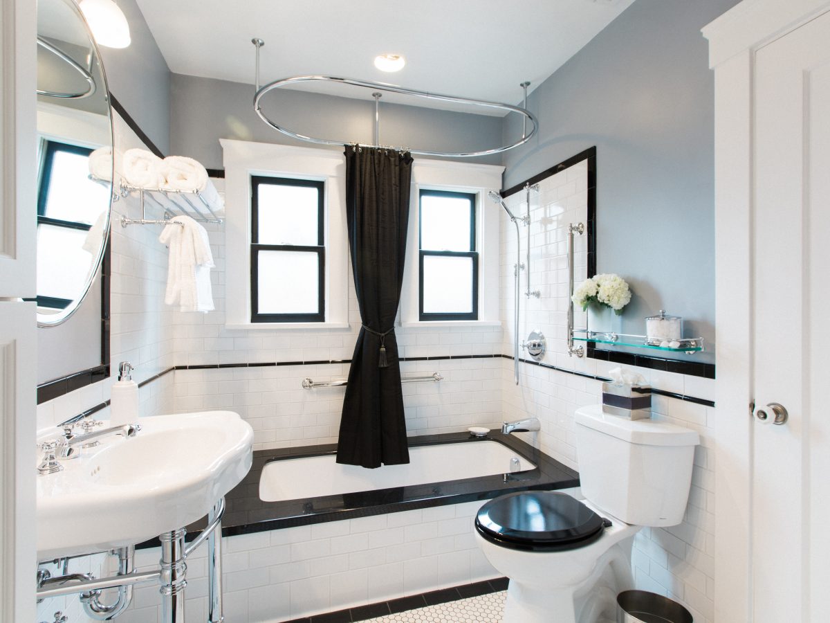 1920s historic bathroom with black granite drop-in tub, white subway tile, and hex mosaic floor — Reveal Interior Design Las Vegas