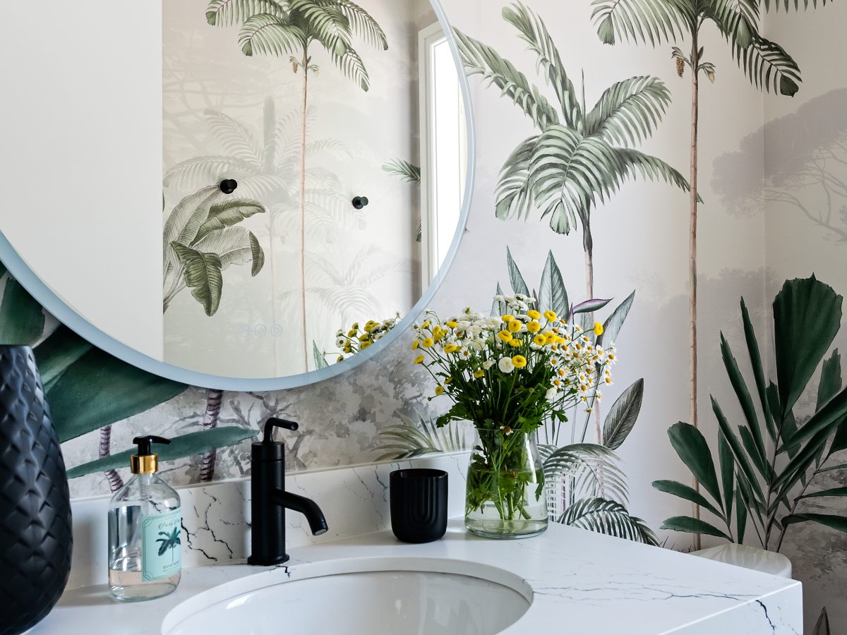 Tropical mural powder bath with white stone vanity and round mirror — Reveal Interior Design Las Vegas