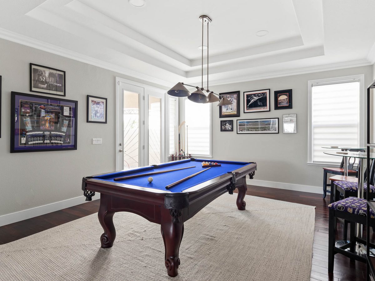 Game room with blue felt billiard table and cherry wood flooring — Reveal Interior Design Las Vegas