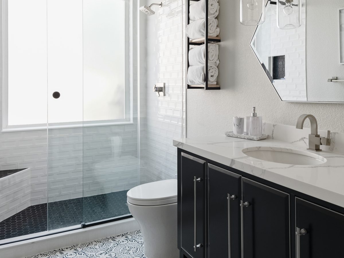 Hall bathroom with encaustic black and white floor tile, furniture-style vanity, and quartz countertop — Reveal Interior Design Las Vegas
