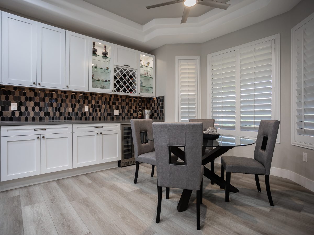 Kitchen breakfast nook with white shaker cabinetry, hex mosaic backsplash, and wine storage — Reveal Interior Design Las Vegas