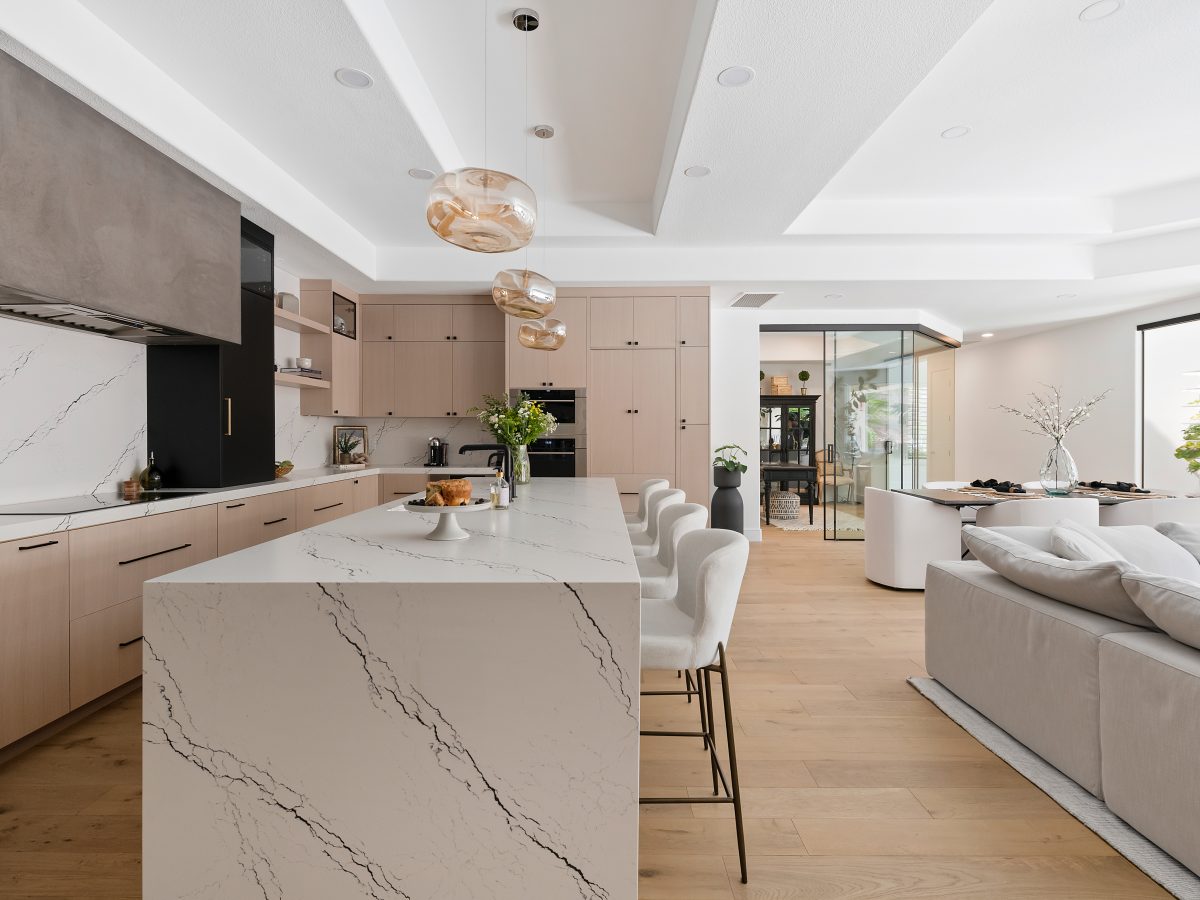 Open-concept kitchen with black-veined white quartz island, whitewashed oak cabinetry, and matte black accents — Reveal Interior Design Las Vegas