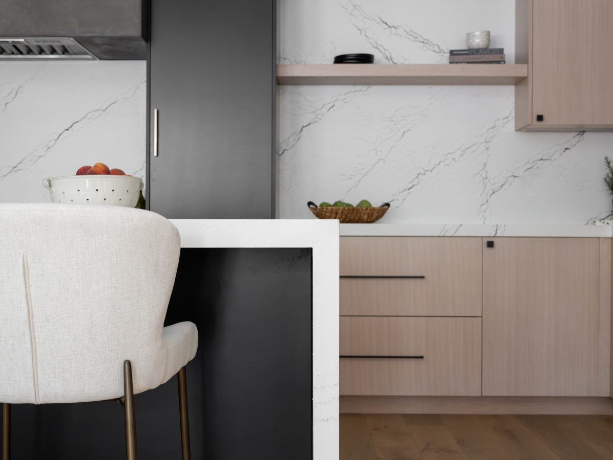 Modern kitchen with white-washed oak cabinetry, black quartz backsplash, and amber pendant lighting — Reveal Interior Design Las Vegas