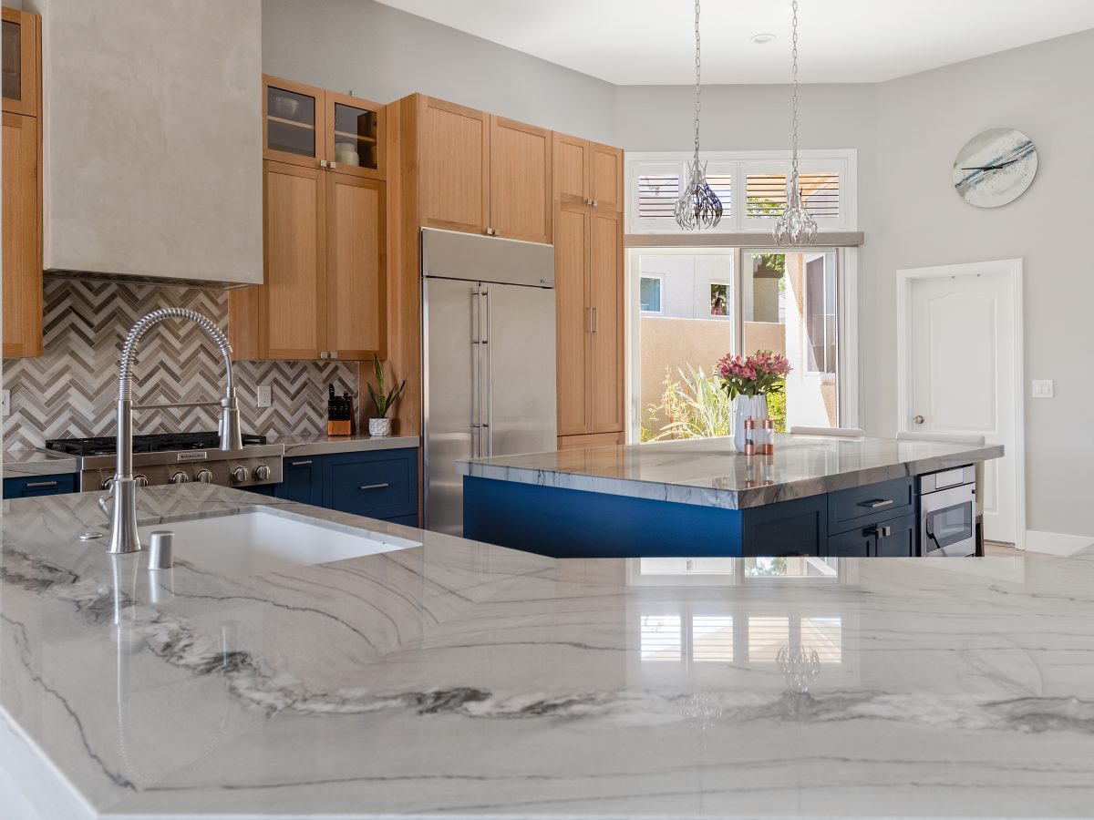 Luxury kitchen with quartzite countertops, dark blue and warm oak cabinetry — Reveal Interior Design Las Vegas