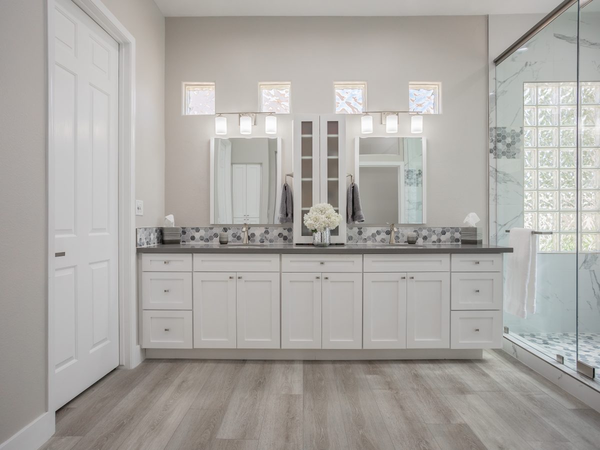 Primary bathroom with white shaker vanity, greige quartz countertops, and marble-look porcelain shower — Reveal Interior Design Las Vegas