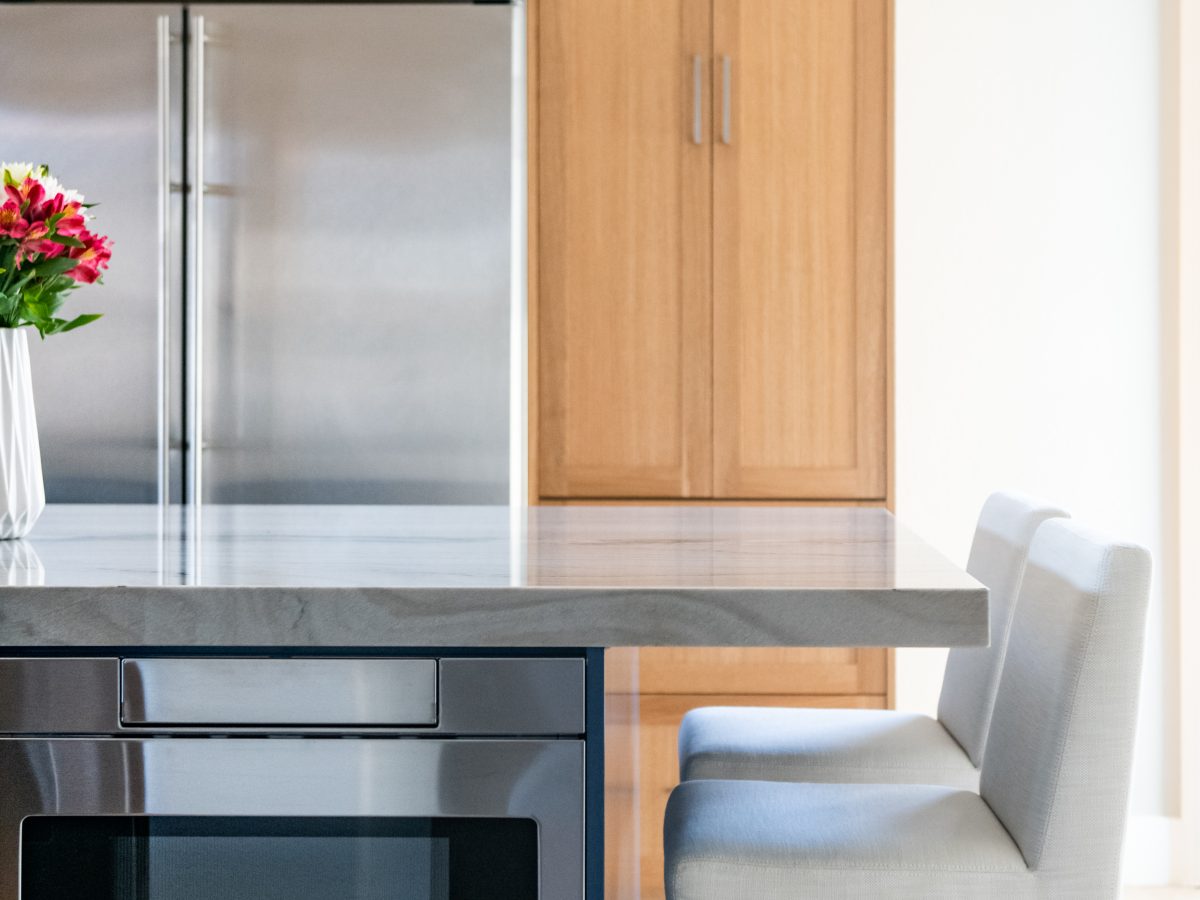 Kitchen with blue island, warm oak cabinetry, and quartzite countertops — Reveal Interior Design Las Vegas