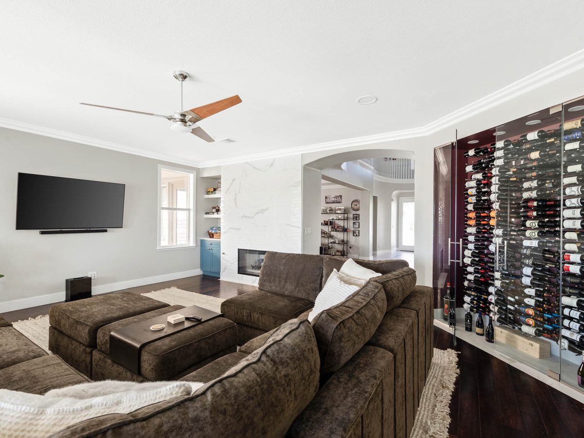 Living room with custom built-in wine storage and dimensional porcelain tile fireplace surround — Reveal Interior Design Las Vegas