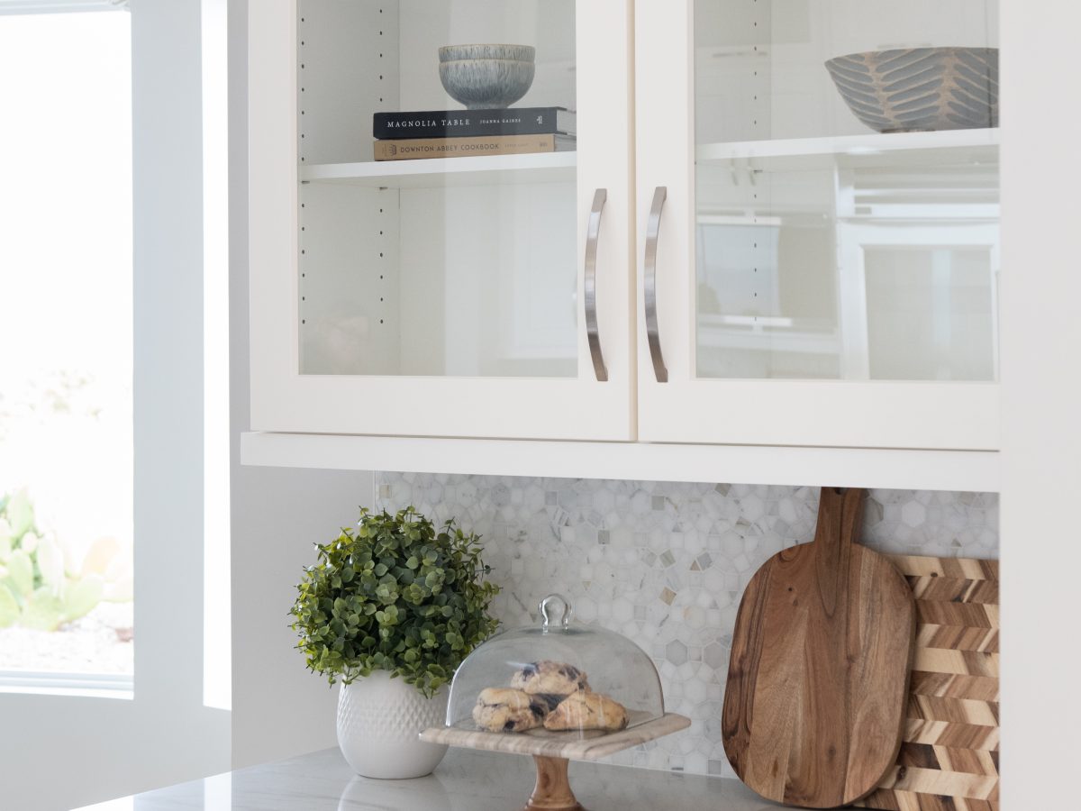 Transitional kitchen butler's pantry with Taj Mahal quartzite countertops and glass-front white cabinetry — Reveal Interior Design Las Vegas