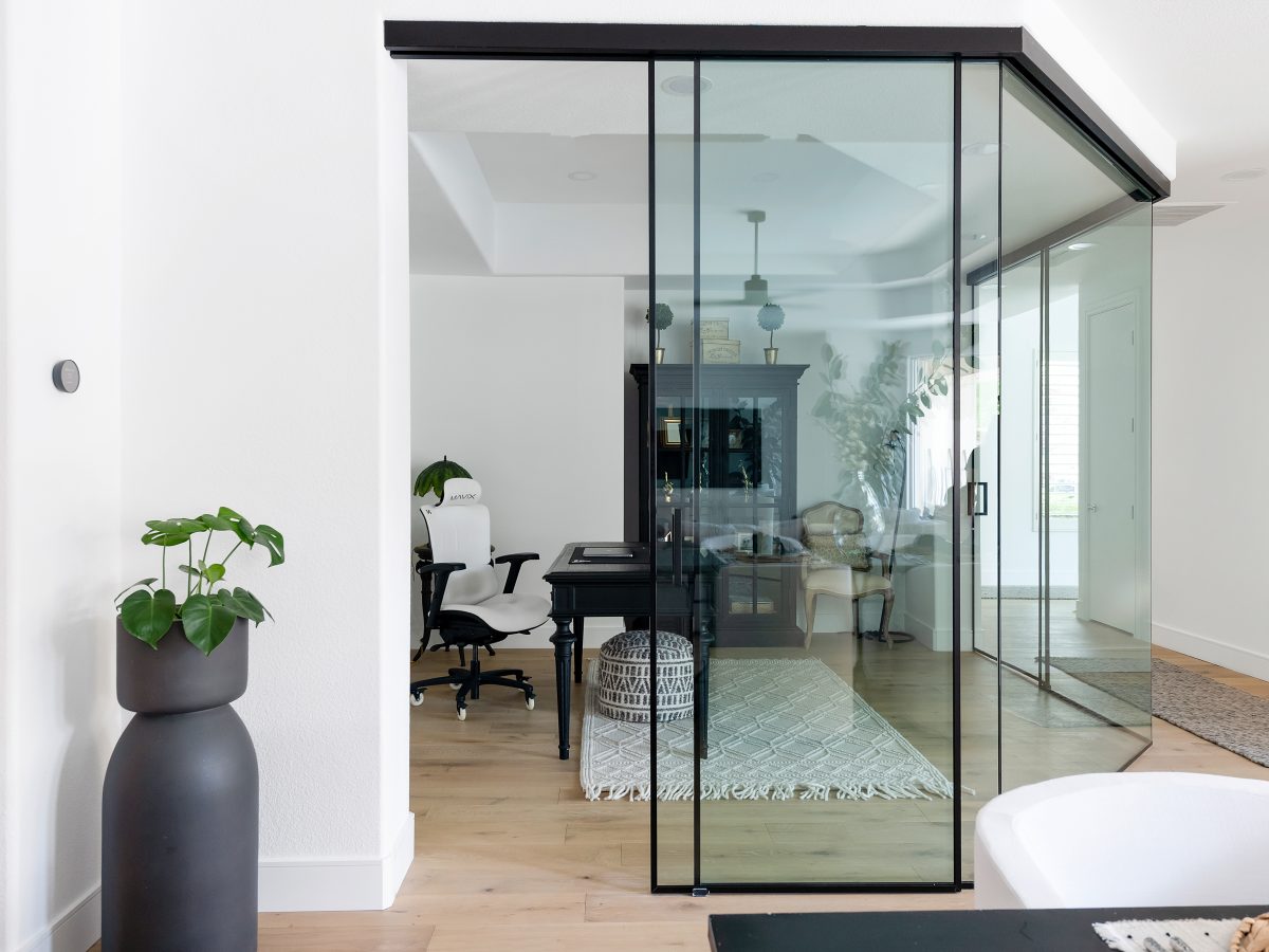 Home office with black metal and clear glass wall enclosure, warm oak engineered flooring — Reveal Interior Design Las Vegas