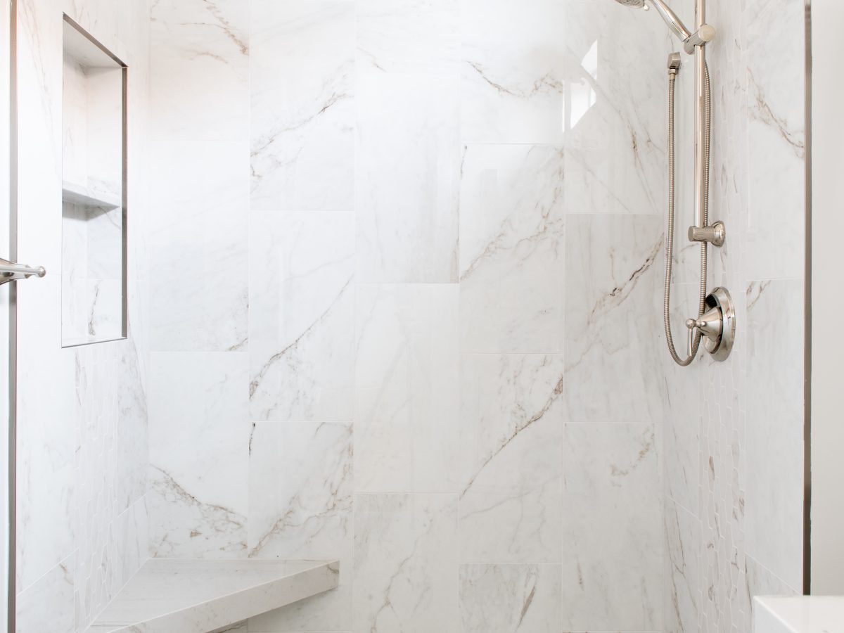 Walk-in shower with marble-look porcelain tile and polished nickel fixtures — Reveal Interior Design Las Vegas