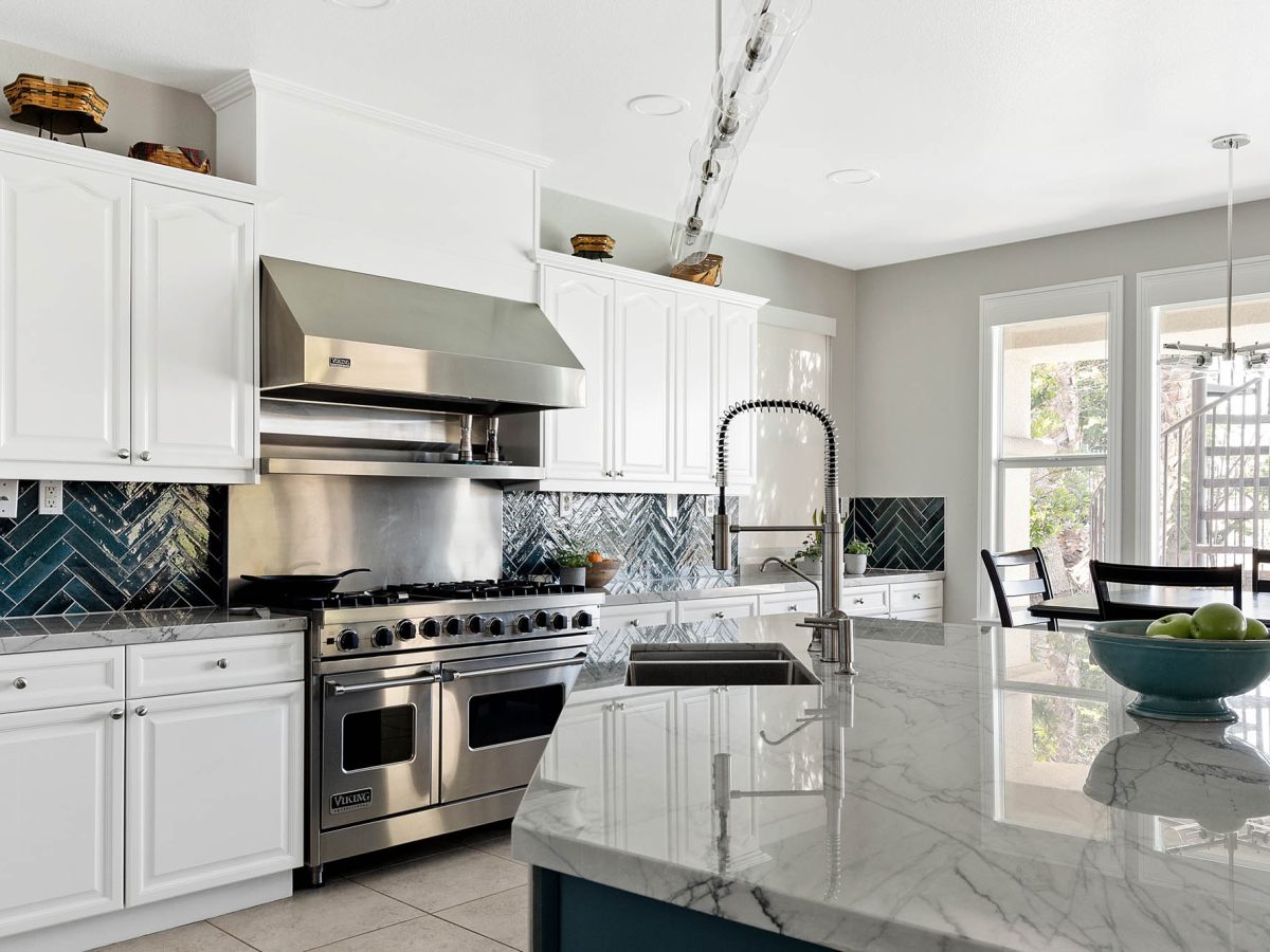Transitional kitchen with blue-veined quartzite countertops and teal herringbone tile backsplash — Reveal Interior Design Las Vegas