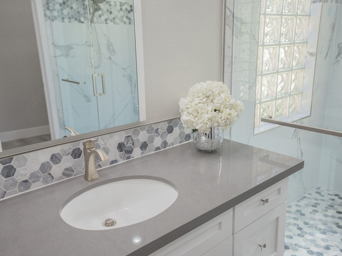 Primary bathroom with greige quartz vanity, hexagon mosaic backsplash, and marble-look porcelain shower — Reveal Interior Design Las Vegas