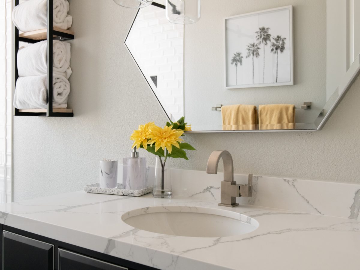 Hall bathroom with quartz countertop, hex mirror, and pendant lighting — Reveal Interior Design Las Vegas