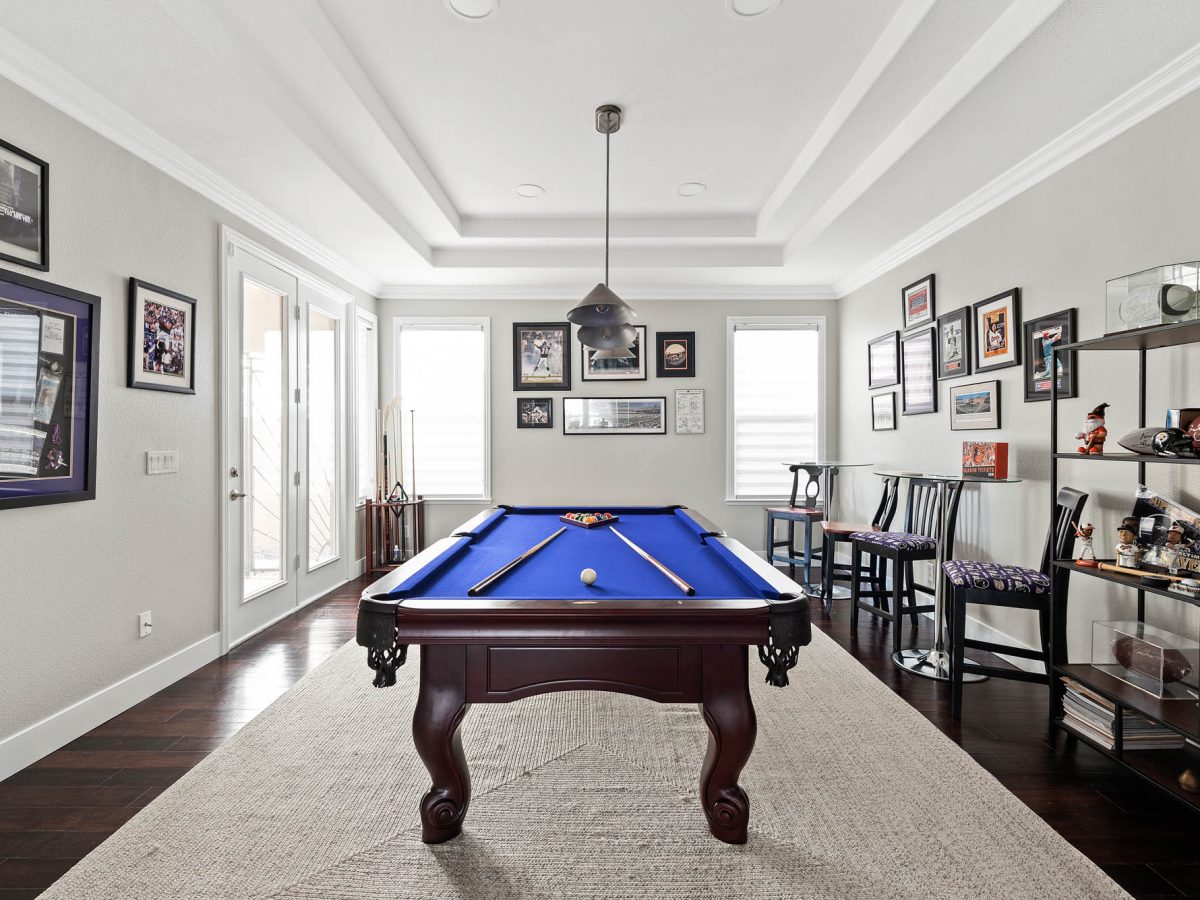 Sports-themed game room with blue billiard table and cherry wood flooring — Reveal Interior Design Las Vegas