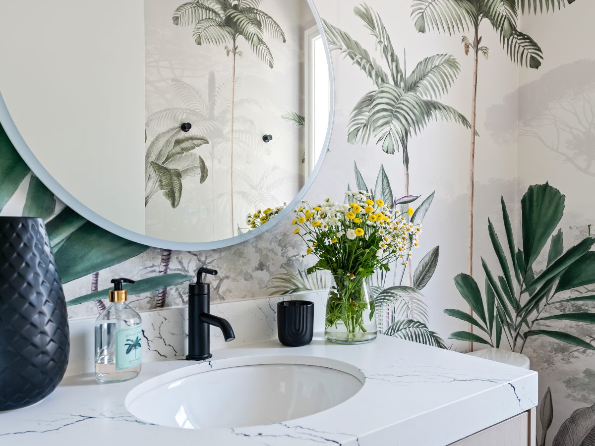 Tropical mural powder bath with white quartz vanity and round mirror — Reveal Interior Design Las Vegas
