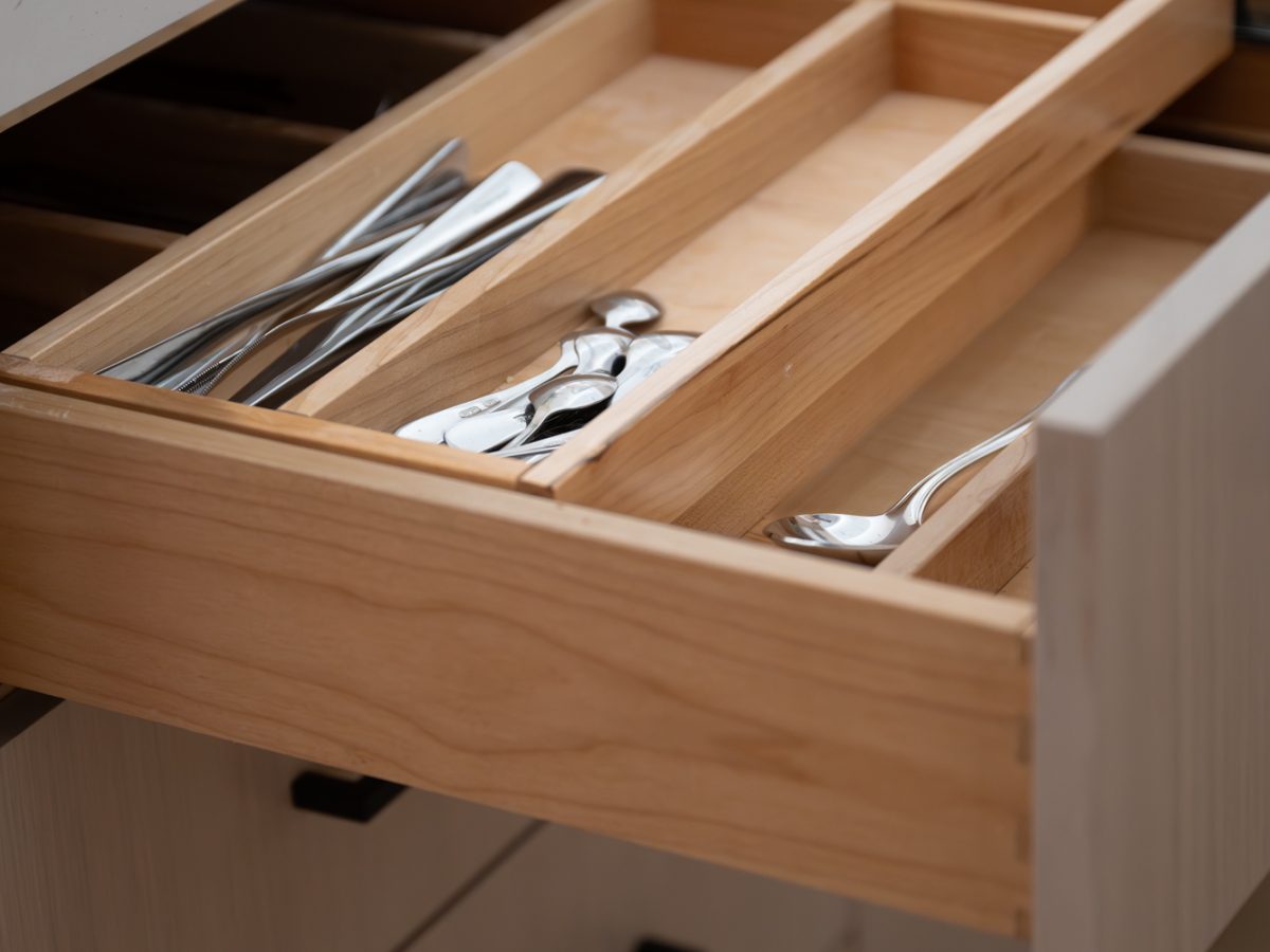 Kitchen drawer organization with warm oak cutlery insert and white quartz countertop — Reveal Interior Design Las Vegas
