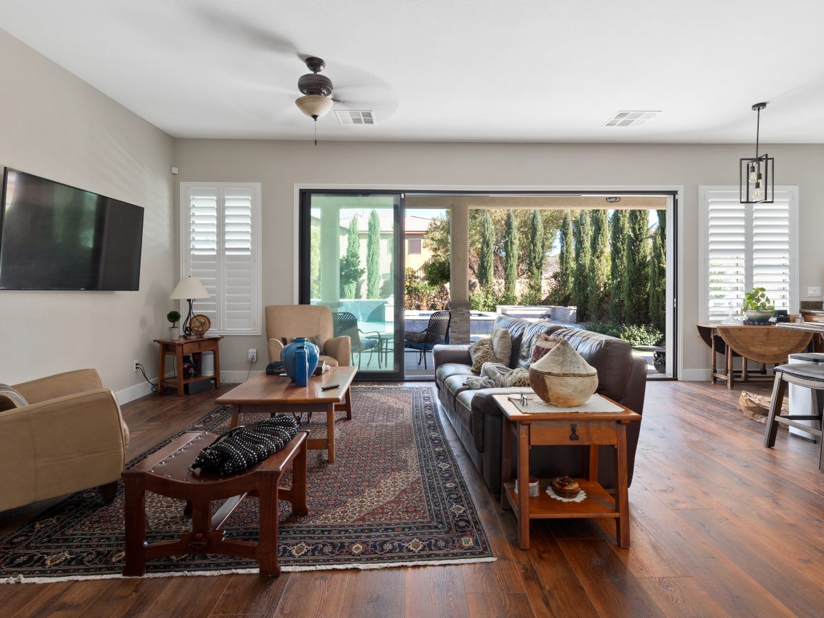 Open-concept living room with expansive black-trim sliding doors and wood flooring — Reveal Interior Design Las Vegas
