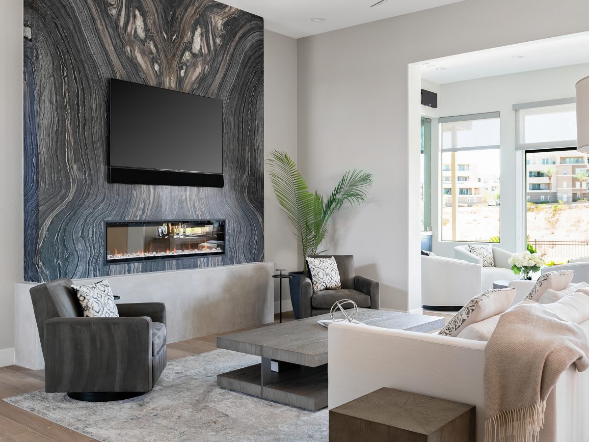Living room with bookmatched leathered quartzite slab fireplace wall and linear fireplace — Reveal Interior Design Las Vegas