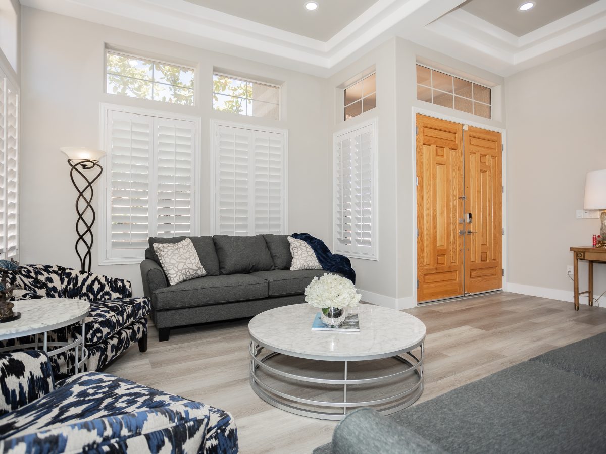 Living room with stone-look round coffee table, patterned accent chairs, and wood-look flooring — Reveal Interior Design Las Vegas