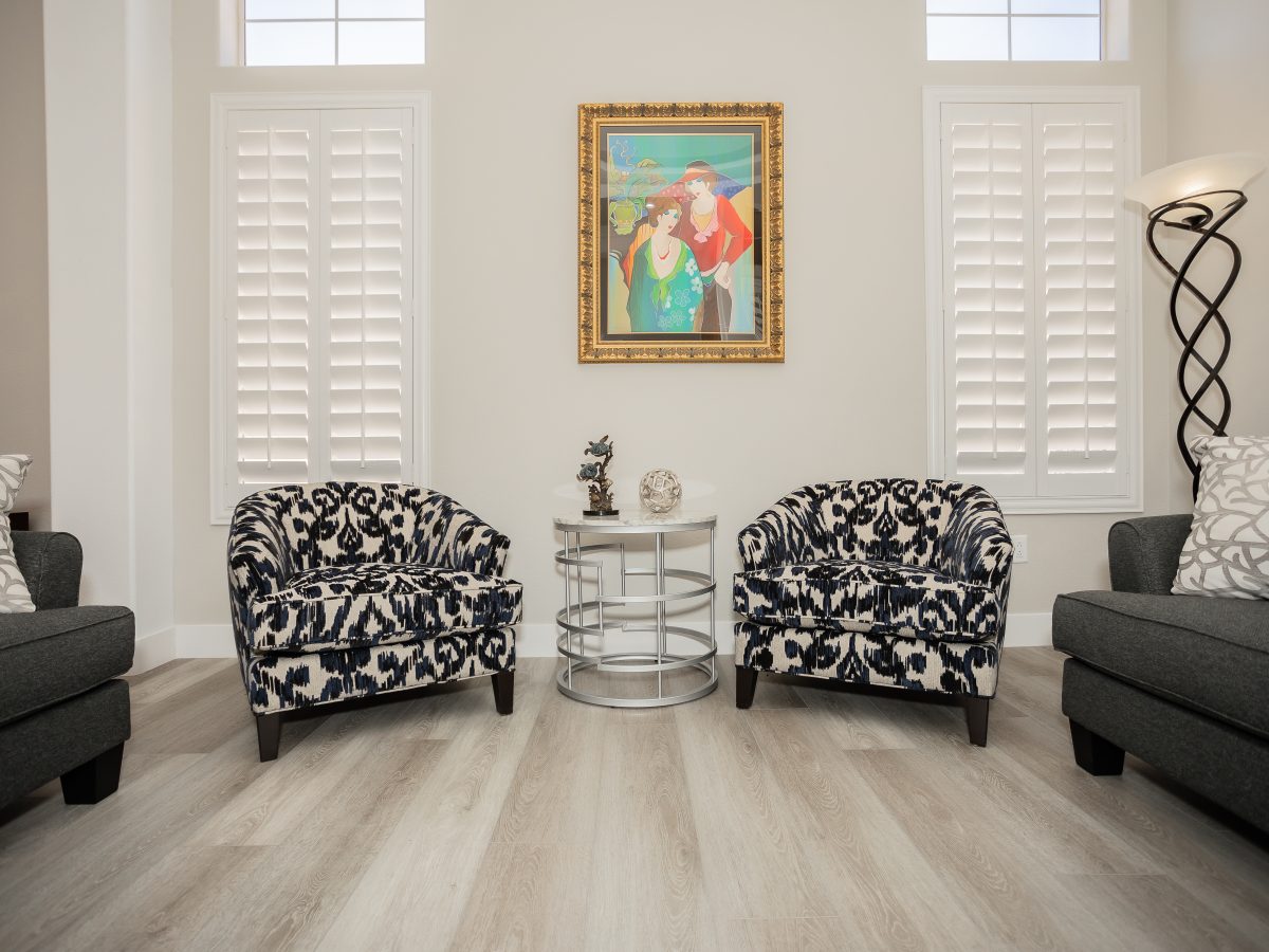 Living room with patterned accent chairs, stone-look coffee table, and gray sofas — Reveal Interior Design Las Vegas